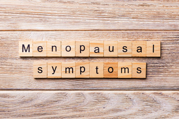 menopausal symptoms word written on wood block. menopausal symptoms text on wooden table for your...