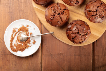 A photo of chocolate muffins, shot from the top on a dark rustic wooden background with cocoa powder and a place for text