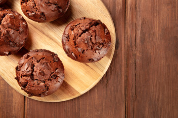 An overhead photo of chocolate muffins on a dark rustic wooden background with a place for text