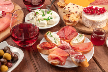 Wine tasting and pairing. Wineglasses with cheese sandwiches and a cheese platter on a dark wooden background