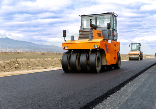 Road roller at road construction site with cloudy blue sky