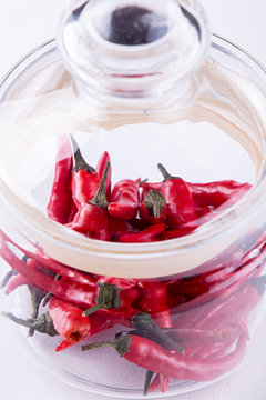 Red small spisy chili peppers in glass jar.