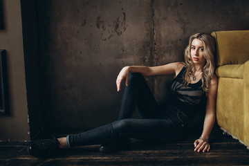 Portrait of a beautiful fashionable woman, blonde, jeans, brown background