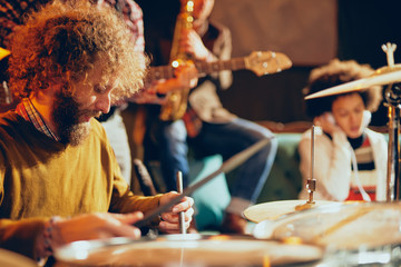 Caucasian drummer playing his instrument while sitting in home studio.