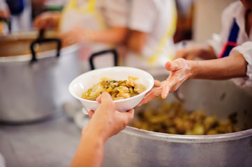 The hand of a beggar received food from a compassionate person : giving food to the poor.