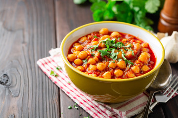 Spicy Chickpea curry Chana Masala in bowl on dark wooden table. Traditional Indian dish. Selective focus.