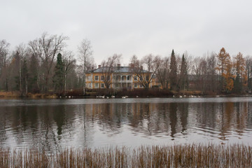 KOUVOLA, FINLAND - NOVEMBER 8, 2018: Wooden Rabbelugn Manor - Takamaan Kartano in dark autumn day. Swans are swimming in water. Wrede family house was built in 1820 on the river Kymijoki bank