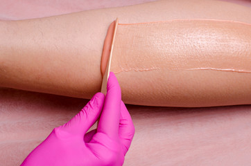 beautician applying wax to females leg to remove hair