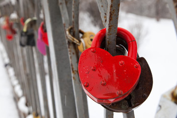  Close-up red heart valentine vintage lock on the bridge in winter. Bridge of lovers in a city park .
