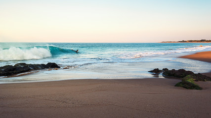 seascape with surfer riding waves beside the shore
