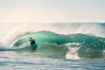 surfer riding a perfect barrel of a wave at sunset