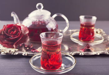 Cups of hot red karkade tea with teapot on the tray