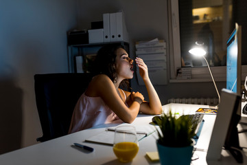 Tired sleepy woman yawning, working at office desk