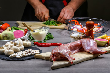 Cooking rabbit meat spice seasoning herbs and vegetables by chef hands on table blank space for text top view. recipe