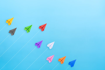 Multicolored paper planes on blue background, Business competition concept with copy space