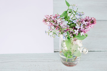 bouquet of lilacs in a vase on a wooden background. space for text