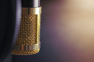 Close-up the head of condenser gold microphone. The light from right side. Artistic style. 