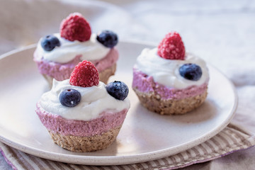 homemade cake with raw strawberries and cashew cream on almond nut dough, healthy vegan food concept. close up
