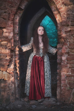 Beautiful girl in long medieval dress in old abandoned castle