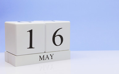 May 16st. Day 16 of month, daily calendar on white table with reflection, with light blue background. Spring time, empty space for text