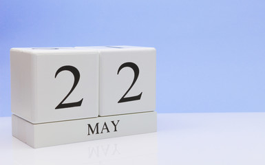 May 22st. Day 22 of month, daily calendar on white table with reflection, with light blue background. Spring time, empty space for text