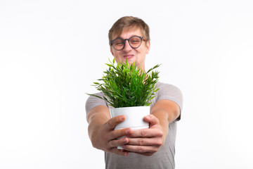 Fun, joke, nerd and geek concept - Funny man holding a flower in a pot over white background