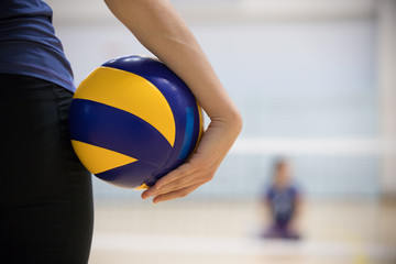A young woman trainer standing in sports hall holding a ball