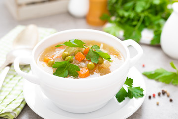 Summer light vegetarian vegetable soup with carrot, potato, cabbage and grean peas on white background. Diet healthy and tasty lunch. Baby food