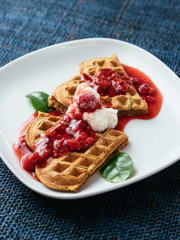 Heart shaped vegan beet waffles with a raspberry sauce. 