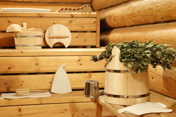 Dry birch broom on the wooden bucket and bath accessories in the sauna.