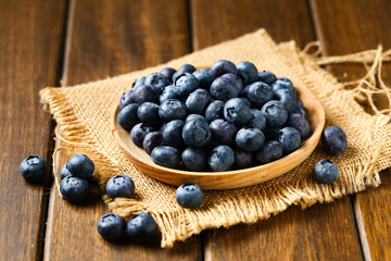 Fresh blueberries in wooden plate on a wooden table