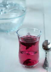 Red carcade tea in transparent glass cup at white wooden background, simple and nice drink picture for calm and peaceful rest time illustration.