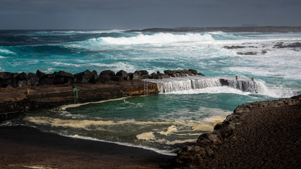 Waves jumping on dock of the fishing cove of La Santa in Lanzarote during a storm.