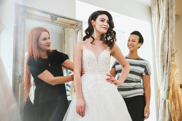 Naklejka premium Beautifu bride choosing wedding dress in a wedding salon