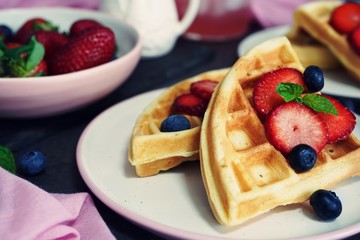 Breakfast Homemade Belgian waffles with berries on dark moody background