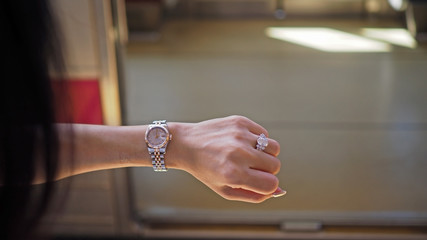 Asian woman checking a time on her left wrist before getting on a train.