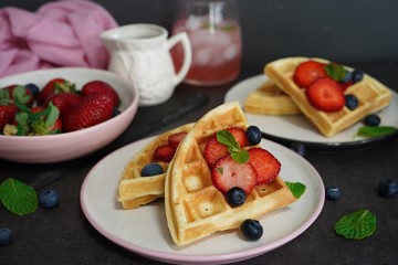 Breakfast Homemade Belgian waffles with berries on dark moody background