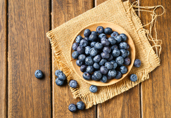 Fresh blueberries in wooden plate on a wooden table
