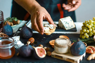 Toasts of cheese, figs and honey in hands in the kitchen. This Fig and Gorgonzola tartines, toast, bruschetta. drizzled with honey