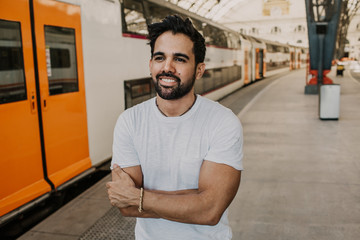 Happy Traveler male discover a big europe city, travel and active lifestyle concept.Bearded hispanic Tourist Man in white tshirt waiting his train on railway station