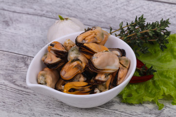 Pickled mussels in the bowl served pepper, garlic and salad