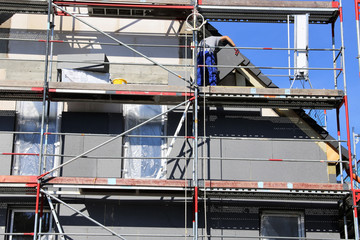Bauarbeiter isolieren eine Hausfassade