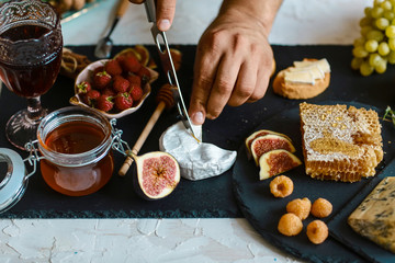 Camembert cheese with figs and nuts in hands in the kitchen. on wooden cutting board. Close up view, square composition