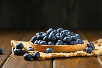 Fresh blueberries in wooden plate on a wooden table