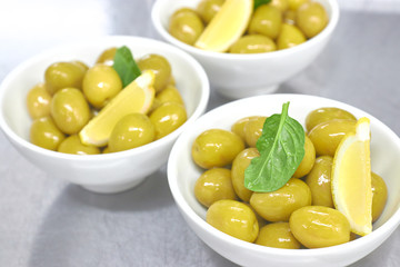 Whole green Greek olives in a white bowl. close up. vertical view of olives.