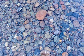colored stones under the crystal clear water of a mountain lake