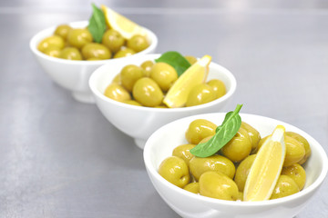 Whole green Greek olives in a white bowl. close up. vertical view of olives.