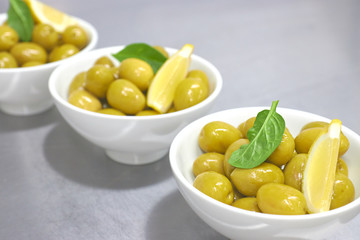 Whole green Greek olives in a white bowl. close up. vertical view of olives.