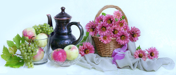 Bouquet of pink and red flowers in a wicker basket and ripe pears ,apples ,grapes.