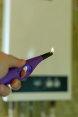 burning kitchen gas lighter against the background of a gas boiler in the background